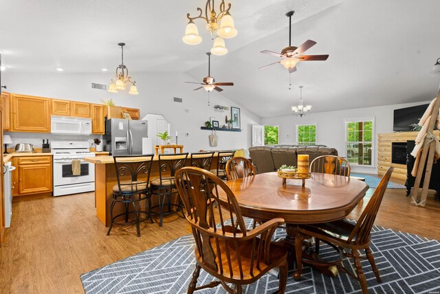 67 Delton Mccauley Rd, Kirby, AR 71950 - dining space with a chandelier, a ceiling fan, a fireplace, light wood-style flooring, and high vaulted ceiling