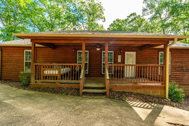 67 Delton Mccauley Rd, Kirby, AR 71950 - view of front of house featuring a ceiling fan, a porch, a shingled roof, and log veneer siding
