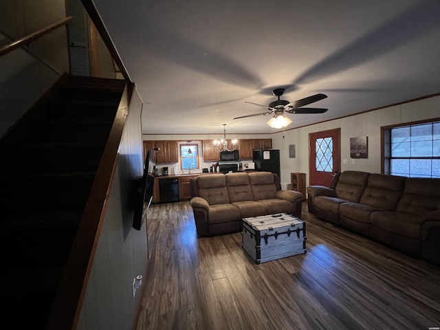 living area featuring ceiling fan with notable chandelier, dark wood-type flooring, visible vents, stairs, and ornamental molding