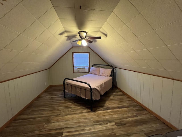 bedroom featuring dark wood-style flooring, vaulted ceiling, wood walls, ceiling fan, and baseboards