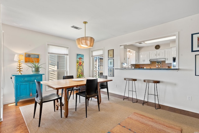 dining space with visible vents, light wood-style flooring, and baseboards