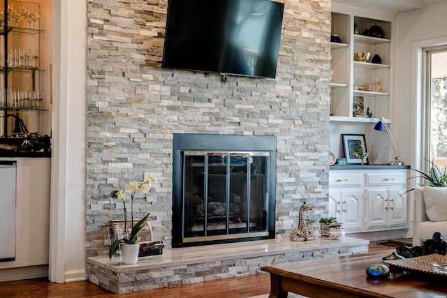 living room with wood finished floors, built in features, and a fireplace