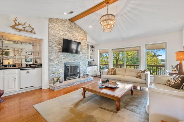 living room with vaulted ceiling with beams, a notable chandelier, light wood-style flooring, and a healthy amount of sunlight