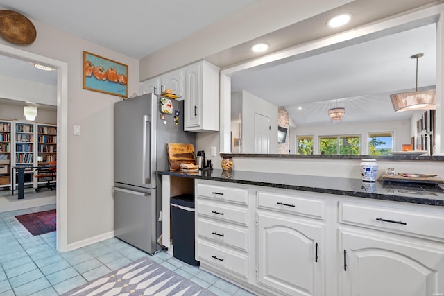 kitchen featuring recessed lighting, dark stone counters, freestanding refrigerator, light tile patterned floors, and white cabinets