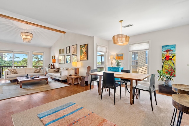 dining room featuring wood finished floors, visible vents, and lofted ceiling with beams