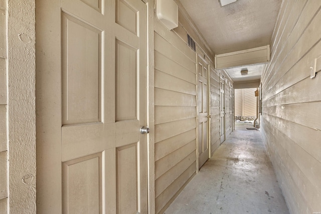 hall featuring concrete flooring and visible vents