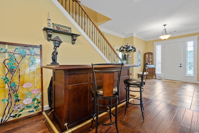 bar featuring pendant lighting, dark wood-style flooring, crown molding, stairway, and baseboards