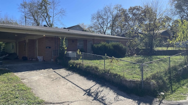 exterior space with fence, an attached carport, concrete driveway, and brick siding