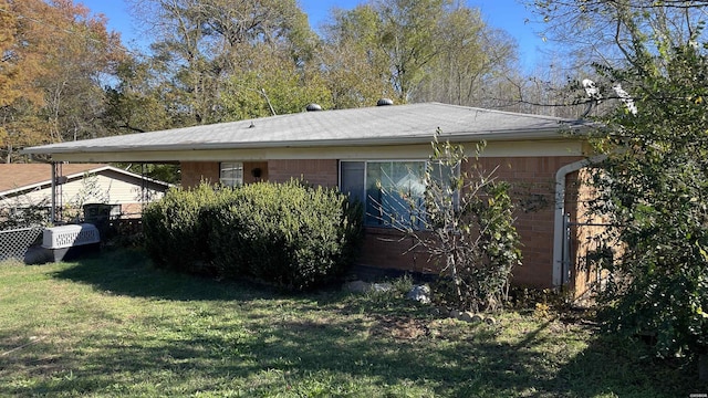 view of home's exterior featuring a carport, brick siding, and a lawn