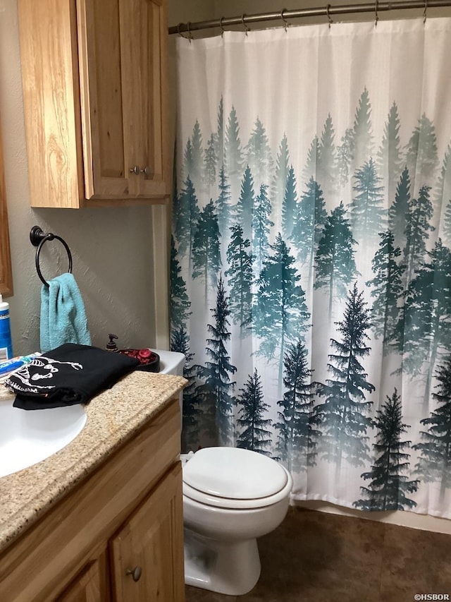 bathroom with a textured wall, vanity, and toilet