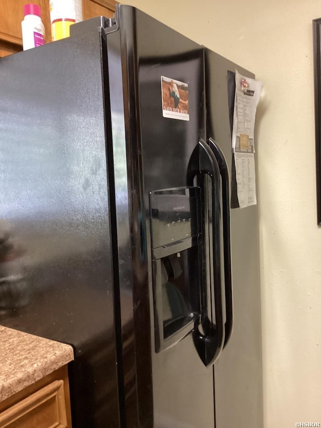 room details with light countertops and black fridge with ice dispenser