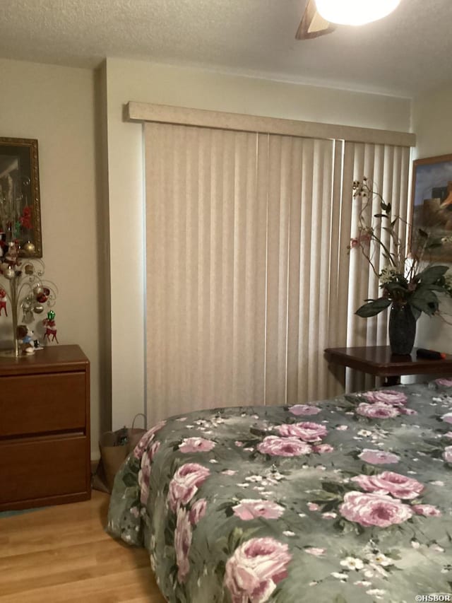 bedroom featuring a ceiling fan, a textured ceiling, and wood finished floors