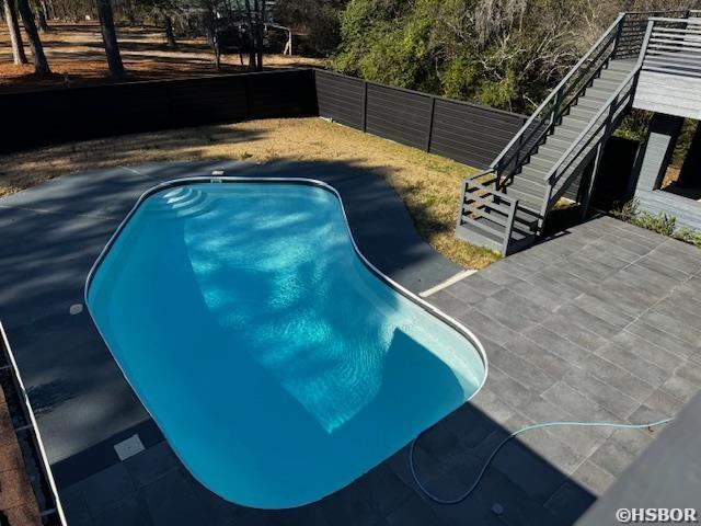 view of swimming pool with a patio area, stairs, fence, and a fenced in pool