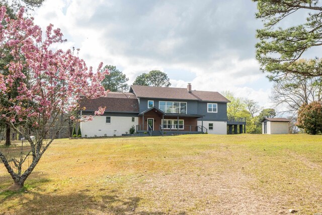 back of property with a storage shed, a lawn, an outdoor structure, and a chimney