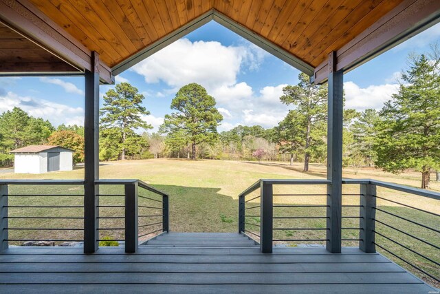 wooden deck featuring a shed, a lawn, and an outdoor structure