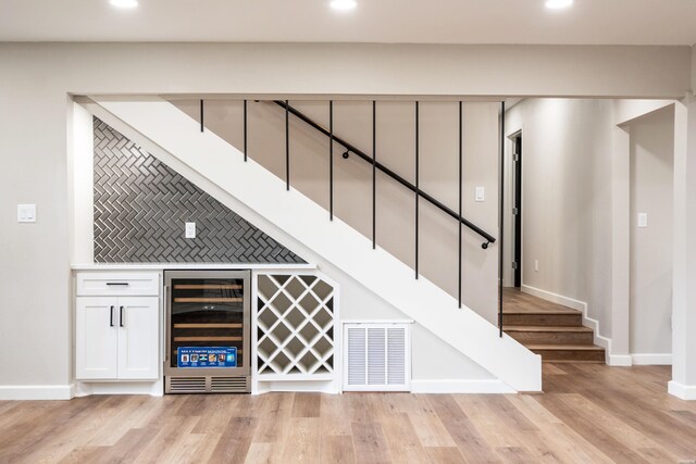 bar featuring beverage cooler, light wood finished floors, visible vents, and recessed lighting