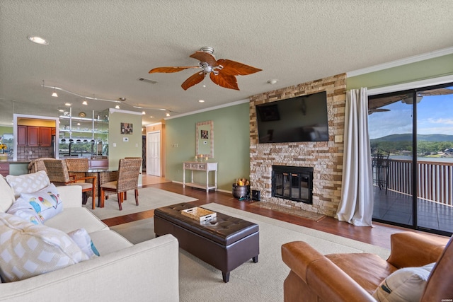310 Kleinshore Rd Unit C9, Hot Springs, AR 71913 - living room featuring a textured ceiling, a ceiling fan, ornamental molding, a stone fireplace, and wood finished floors