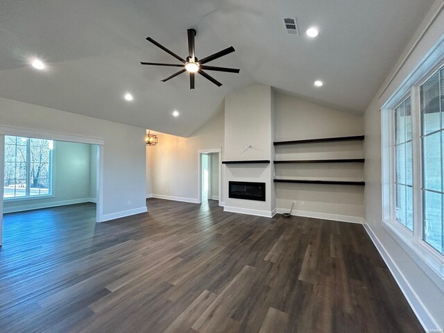 unfurnished living room featuring dark wood-style floors, lofted ceiling, recessed lighting, a glass covered fireplace, and baseboards