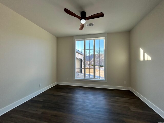 spare room with dark wood-type flooring, visible vents, baseboards, and a ceiling fan