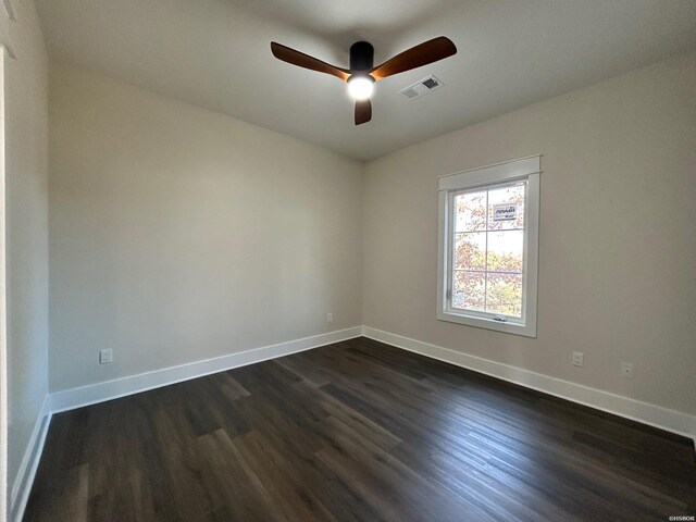 empty room featuring dark wood-style floors, visible vents, baseboards, and a ceiling fan