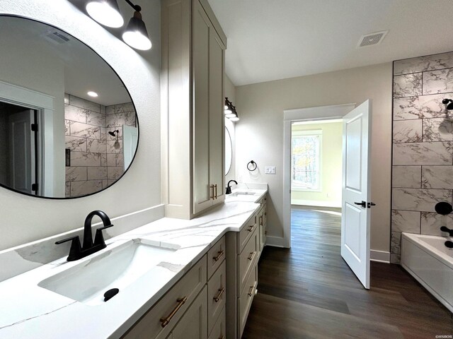 full bath featuring double vanity, wood finished floors, a sink, and visible vents