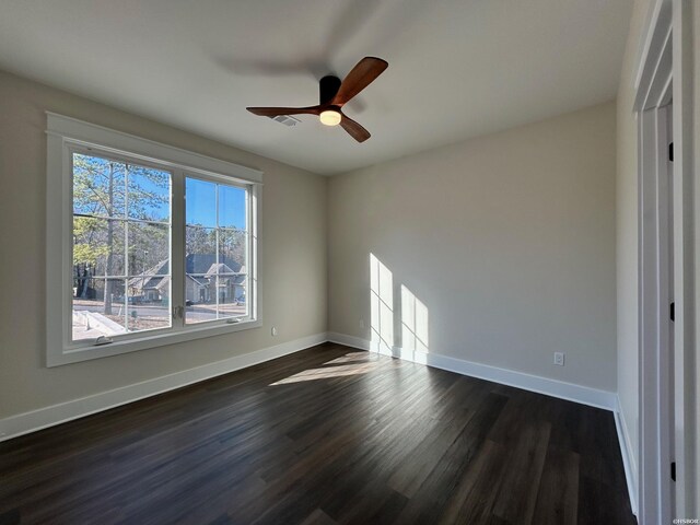 spare room featuring dark wood-style floors, baseboards, and a ceiling fan