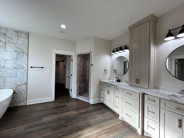 full bath featuring wood finished floors, vanity, baseboards, a freestanding bath, and a stall shower