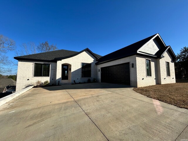 view of front of home featuring a garage, concrete driveway, and brick siding