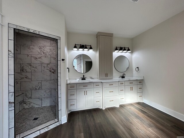 full bathroom with double vanity, baseboards, a sink, and wood finished floors