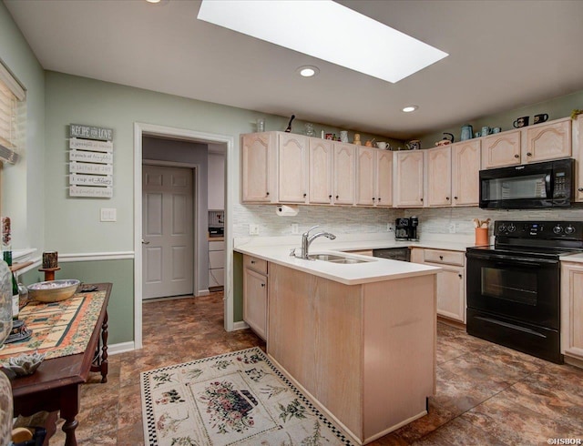 kitchen with a peninsula, light brown cabinetry, a sink, black appliances, and a skylight