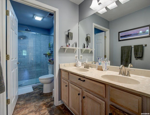 full bath featuring a sink, a shower stall, toilet, and double vanity