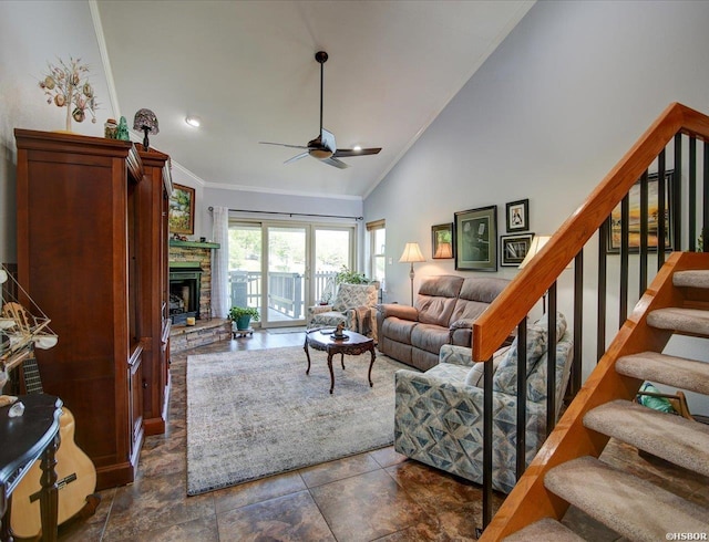 living area with a ceiling fan, a stone fireplace, crown molding, high vaulted ceiling, and stairs