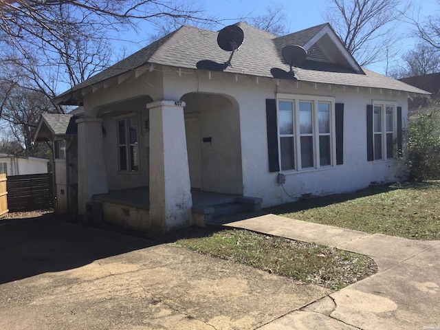 view of front of home with a shingled roof, fence, and stucco siding