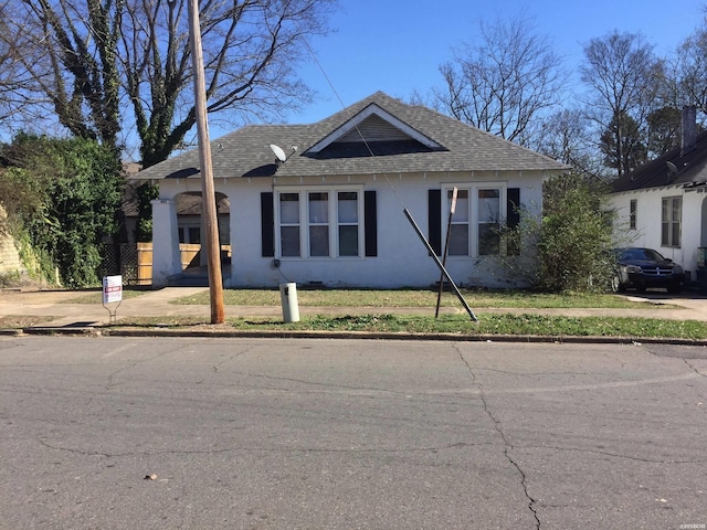 view of front facade with a shingled roof and stucco siding