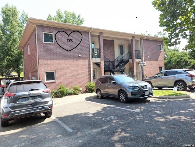 view of property with uncovered parking and stairs