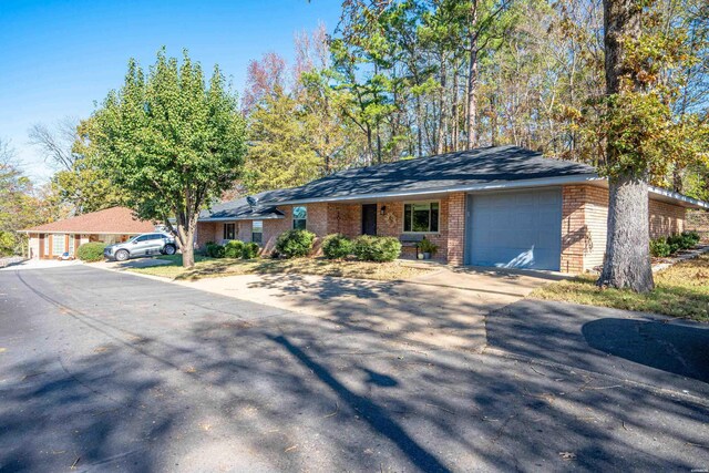 ranch-style house featuring concrete driveway, brick siding, and an attached garage