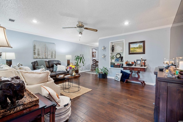 living room with dark wood-style floors, built in shelves, crown molding, visible vents, and a textured ceiling