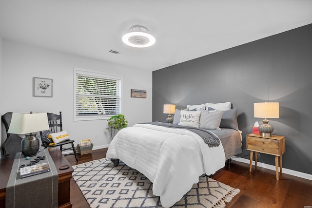 bedroom with dark wood-style floors, visible vents, and baseboards