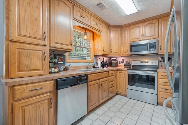 kitchen with a textured ceiling, a sink, visible vents, light countertops, and appliances with stainless steel finishes