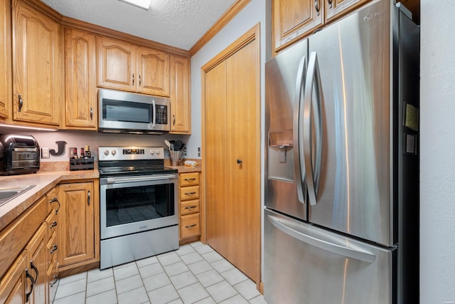 kitchen featuring light tile patterned floors, appliances with stainless steel finishes, light countertops, crown molding, and a textured ceiling