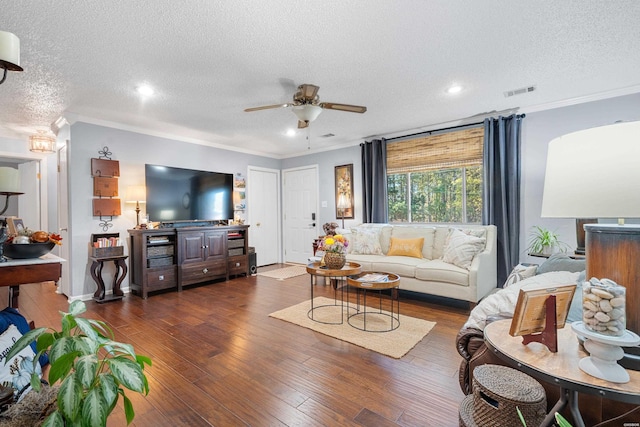 living area featuring visible vents, a ceiling fan, ornamental molding, dark wood-type flooring, and a textured ceiling