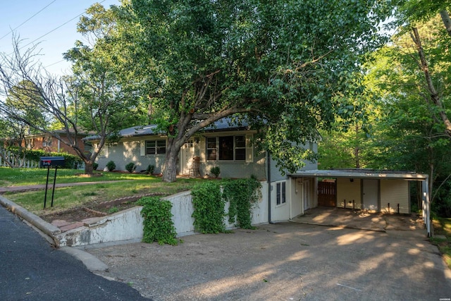ranch-style house featuring driveway, a carport, brick siding, and a front yard