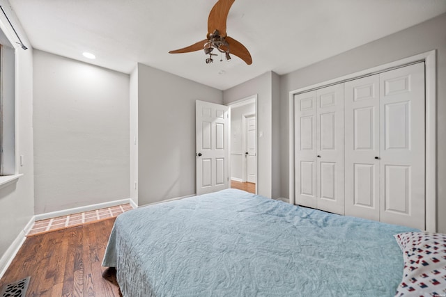 bedroom with baseboards, wood finished floors, a ceiling fan, and a closet