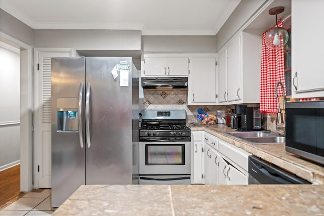 kitchen featuring stainless steel appliances, under cabinet range hood, light countertops, white cabinets, and ornamental molding