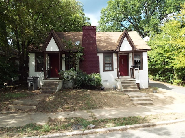 tudor home featuring crawl space, a chimney, and stucco siding