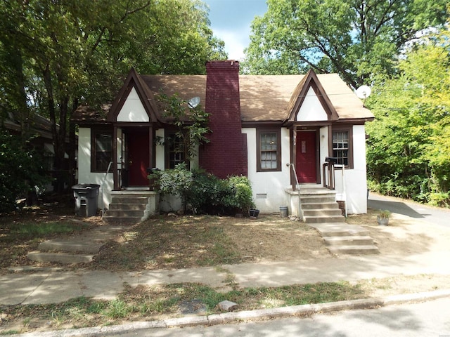 tudor-style house featuring crawl space, stucco siding, and a chimney