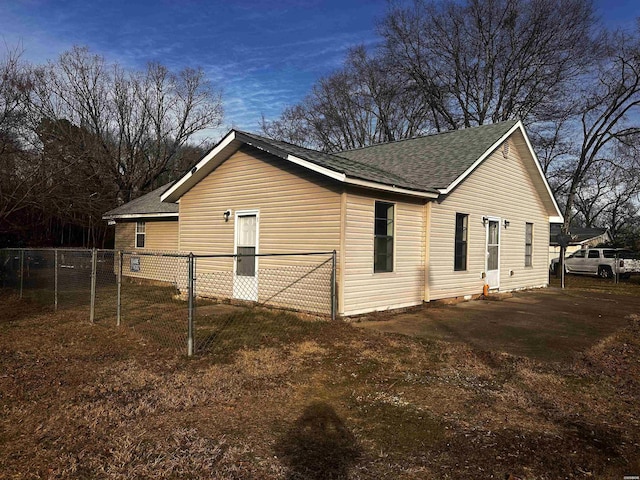 view of side of home with fence and roof with shingles