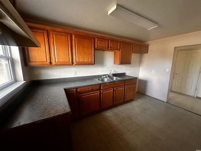 kitchen featuring dark countertops, brown cabinetry, and a sink