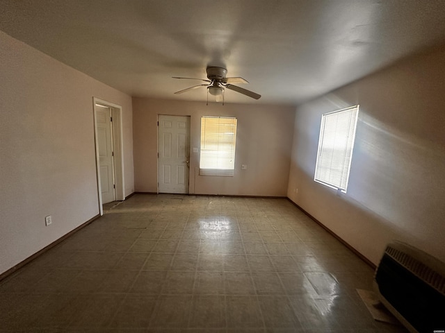 unfurnished room with a ceiling fan, heating unit, plenty of natural light, and baseboards