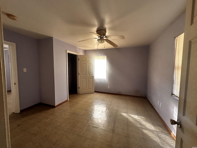 spare room featuring a ceiling fan, baseboards, and light floors